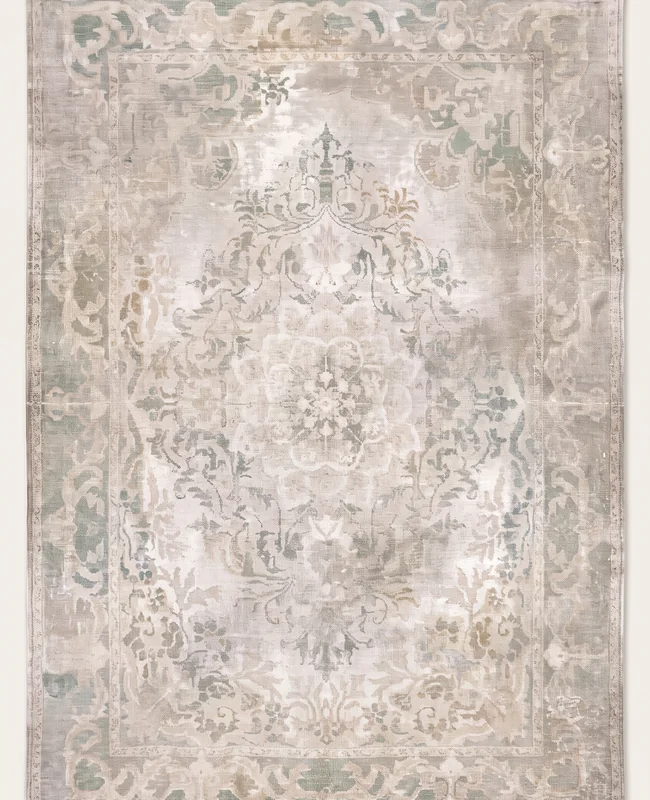 A soft ivory and beige rug with a faint medallion pattern and a gently worn, vintage look.